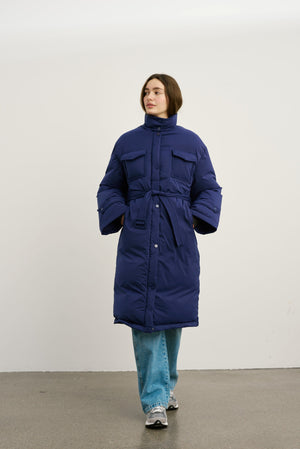 A model showcases a stylish navy blue puffer coat with a belted waist and large pockets, perfect for winter by MEOTINE.