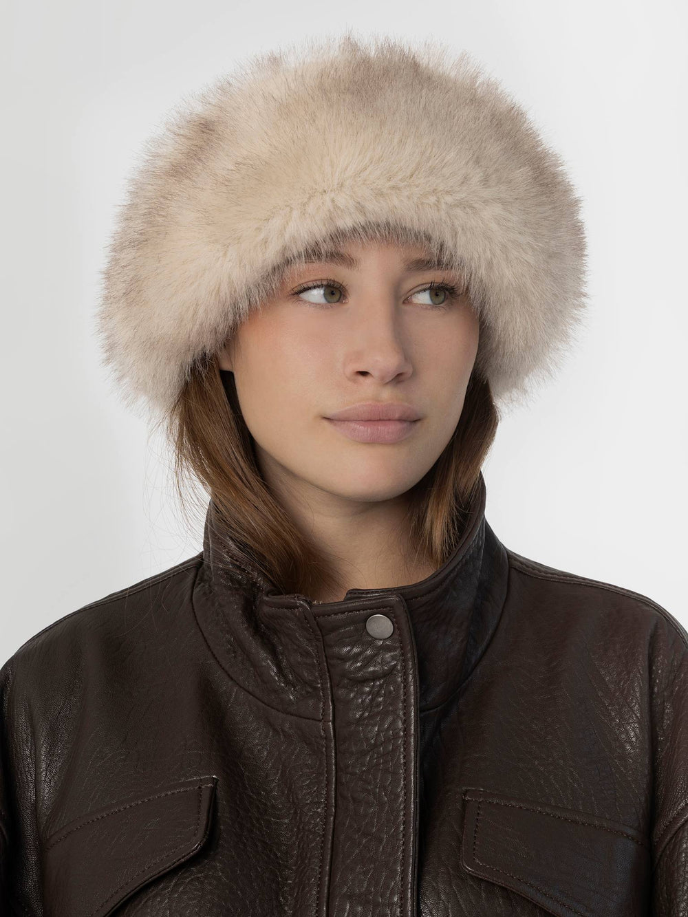 A model wearing a soft, fluffy beige hat paired with a dark brown leather jacket, showcasing MEOTINE's stylish winter accessory.