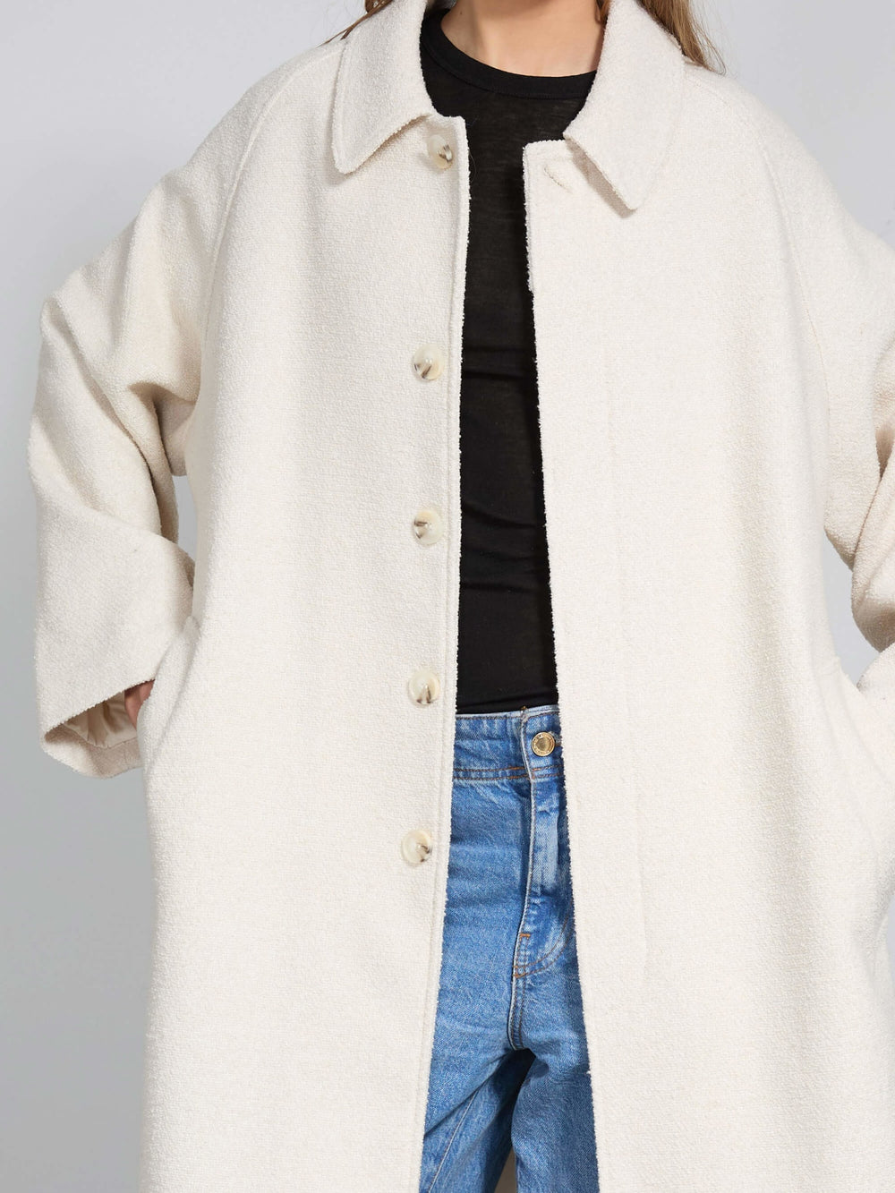 A model showcases a cozy, oversized cream coat by MEOTINE, paired with relaxed blue jeans and a simple black top.