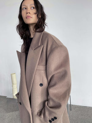 A model showcases a stylish oversized brown coat with a tailored fit, featuring large buttons and a chic collar, by MEOTINE.